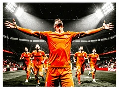 A male athlete in a bright orange jersey celebrating a goal on a football pitch, arms spread wide, head tilted back in triumph, teammates rushing toward him from behind, stadium floodlights blazing down from above creating sharp highlights on his face and kit, electric and triumphant atmosphere. Raw photocopy zine aesthetic, brutalist DIY print energy with high-contrast pure white #FFFFFF and pure black #000000, disrupted by aggressive red #FF0000 accents and muted grey #F2F2F2 mid-tones. Flat hard daylight with crushed shadows and no soft falloff. Style: brutalist zine. Mood: confrontational.